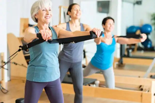 Toning Arms After 60: Empowering Womens Fitness Through Effective Weight Training 2 older woman doing weight training Wollaton and resistance in the gym to tone upper arms
