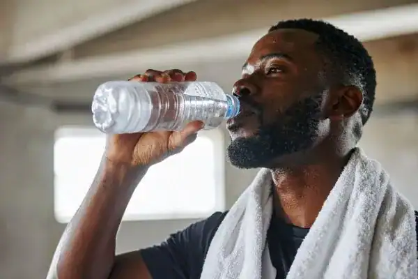 Image of man drinking water to improve hydration Wollaton after work out.